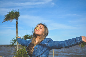 Blonde girl wearing yellow nozscreen by palm trees