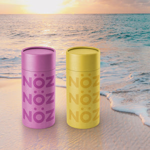 Purple and yellow nozscreen sticks on beach by ocean